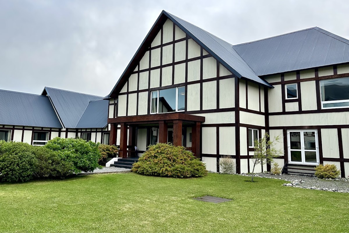 Tudor-style building with dark timber framing and cream walls at EOLO Patagonia's Spirit, featuring manicured lawn and shrubs in front.