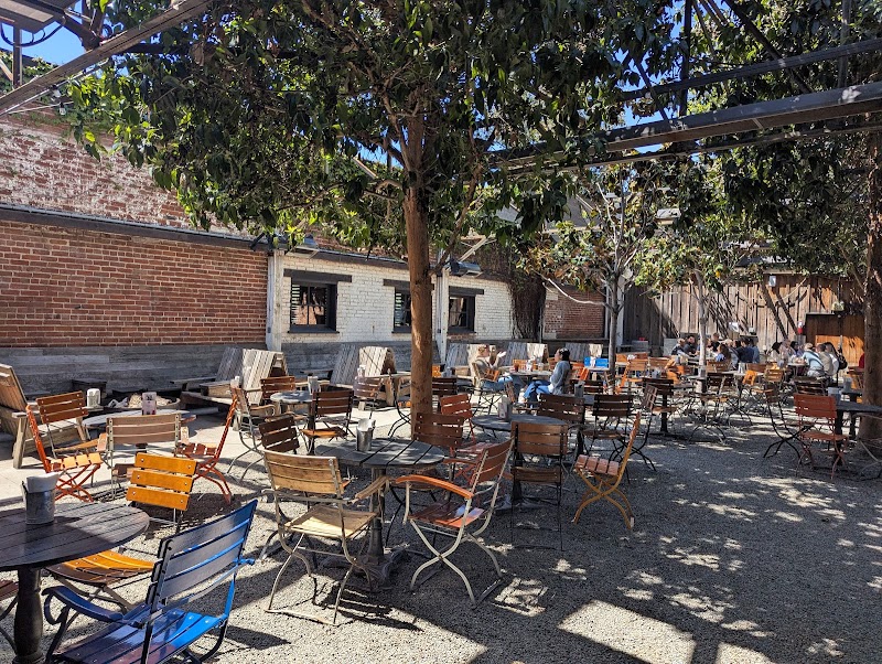 Open-air beer garden with tree grove and bonfires