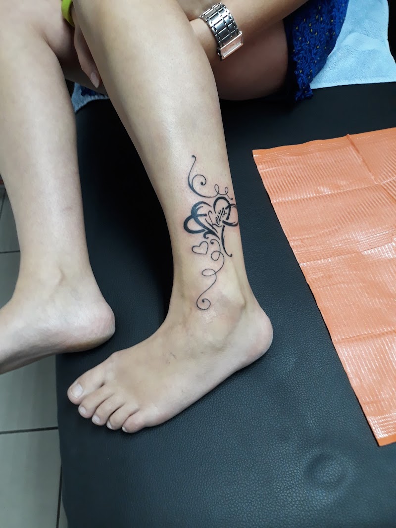 Fineline infinity hart tattoo met naam 'Vera' en krullen op enkel.