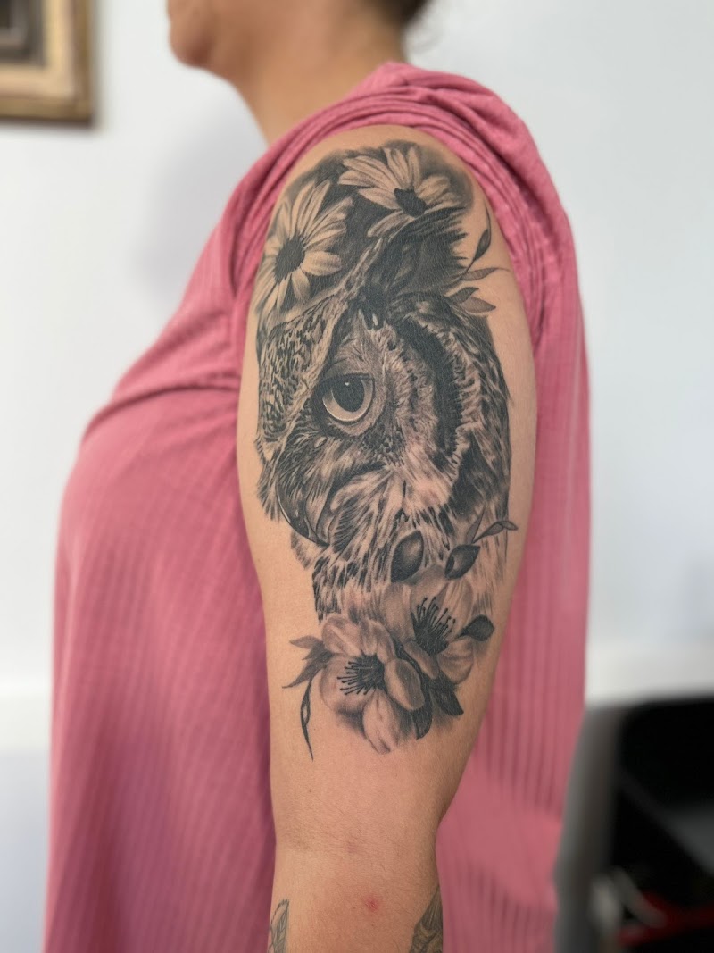 Realistische uil met bloemen op bovenarm.