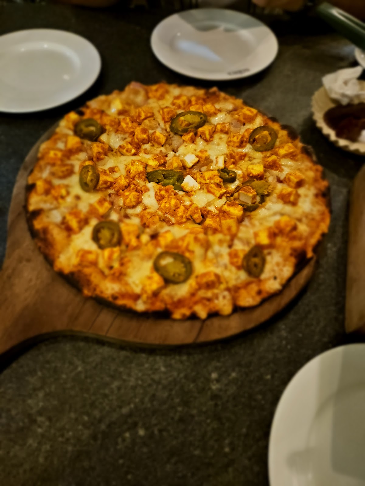 Glen's Bakehouse's signature pizza topped with spicy jalapeños and creamy paneer, showcasing their flair for bold flavors.