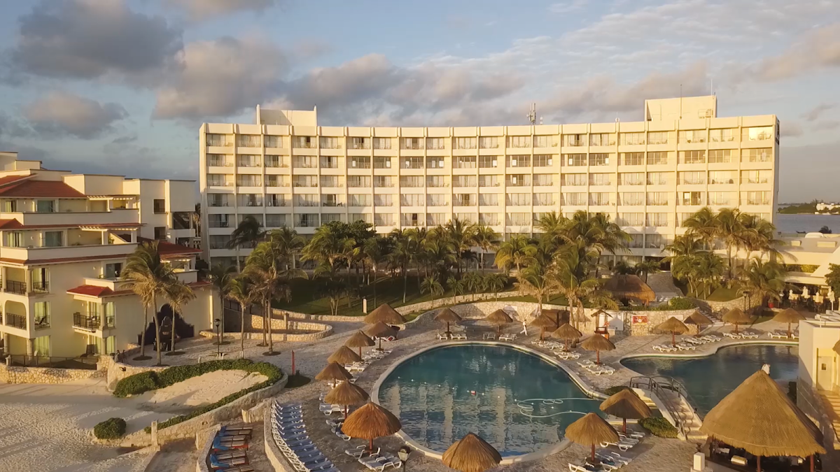 Rooftop lounge area at Grand Park Royal Cancún with illuminated hotel buildings, colorful seating clusters, and cabanas at dusk.