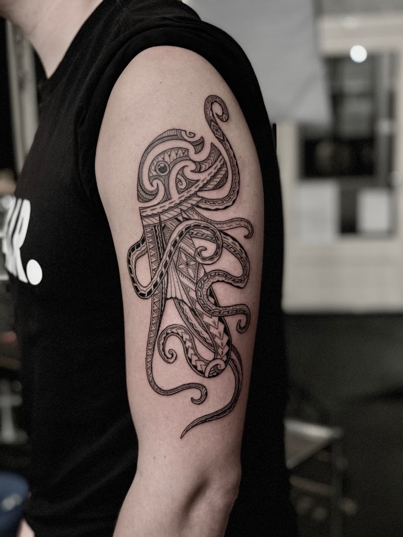 Zwart-wit tribal octopus tattoo op de bovenarm met geometrische patronen.