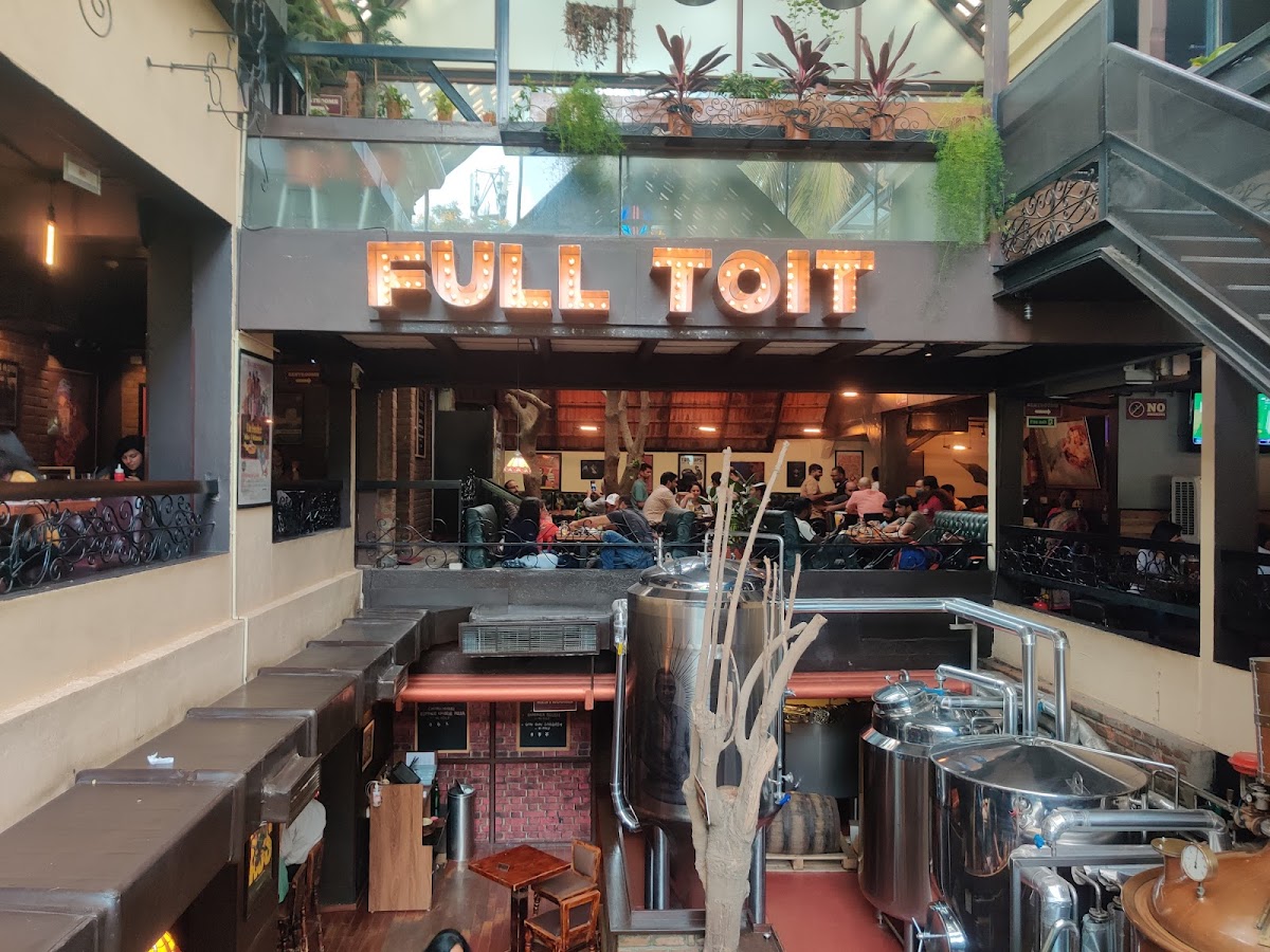 Interior view of a bustling restaurant with brewing equipment visible.