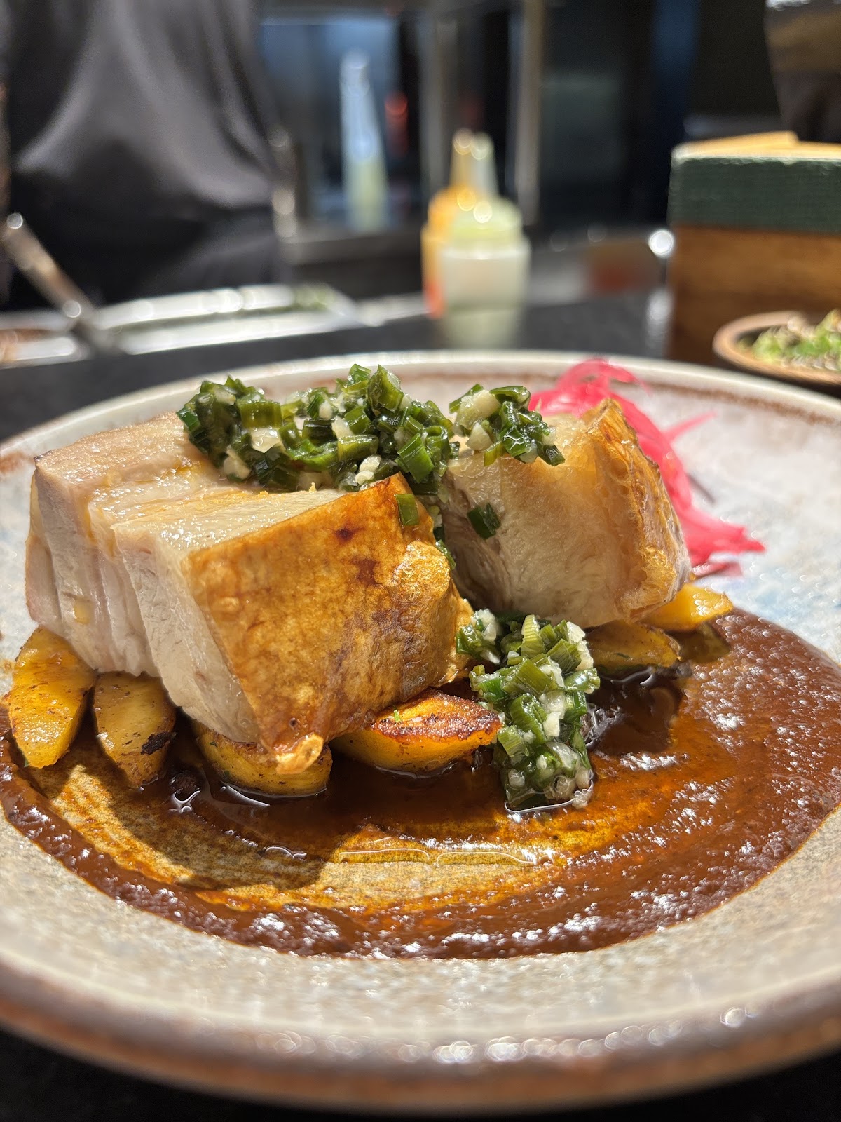 Comal's perfectly seared pork belly with a vibrant chimichurri and a rich, savory sauce.