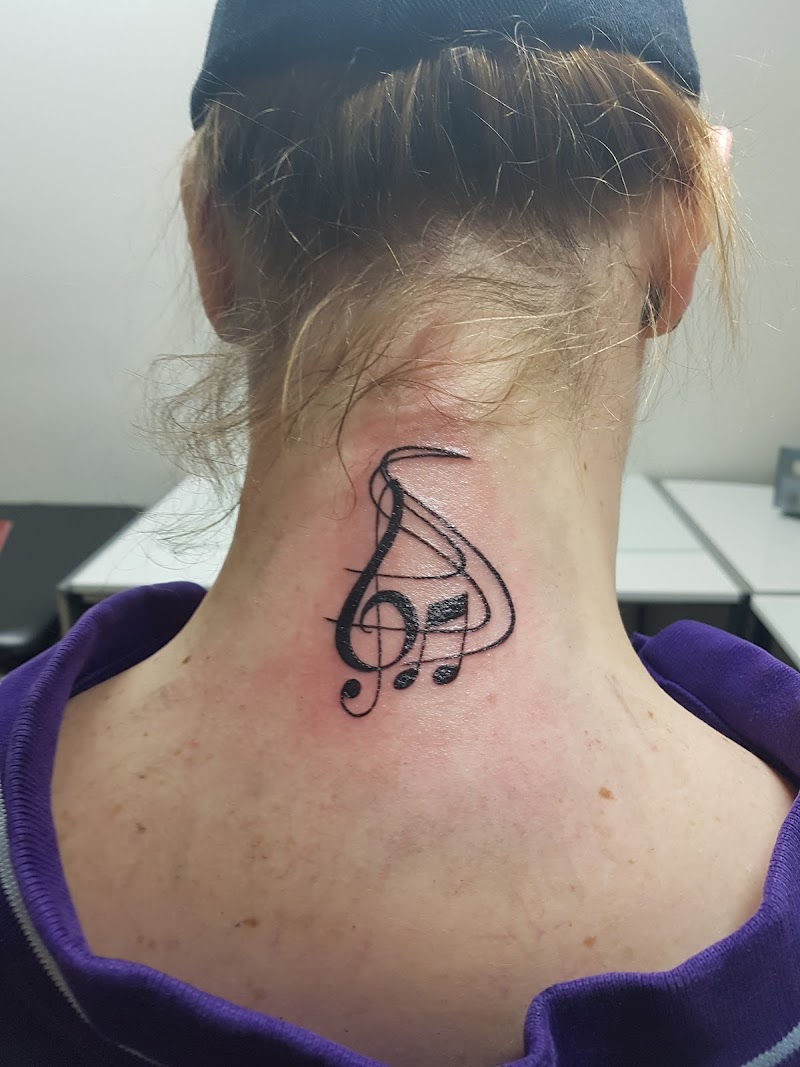 Zwarte muzieksleutel en noten tattoo in de nek.