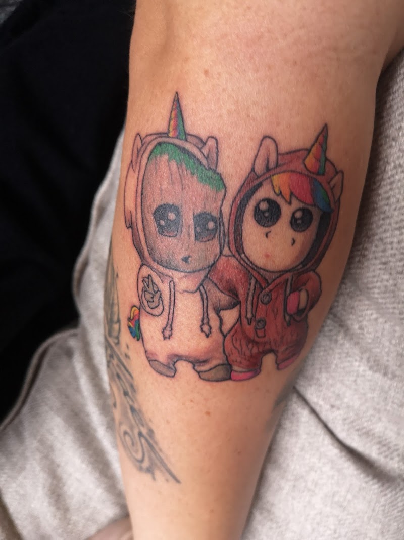 Schattige Baby Groot en eenhoorn karakter in onesies op bovenarm.